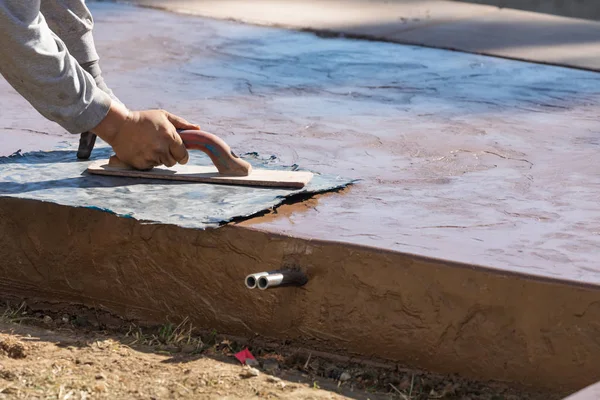 Trabajador de la construcción aplicando presión a la plantilla de textura en cemento húmedo — Foto de Stock