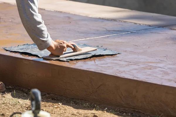 Trabajador de la construcción aplicando presión a la plantilla de textura en cemento húmedo — Foto de Stock