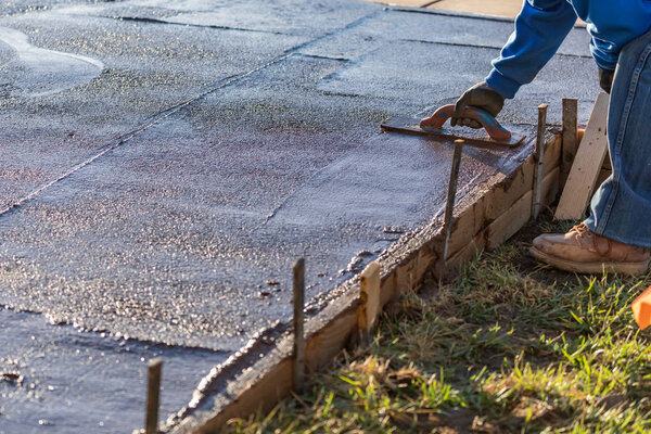 Работник строительства сглаживание мокрого цемента с помощью лопаточных инструментов
