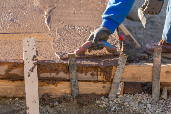 Работник строительства сглаживание мокрого цемента с помощью лопаточных инструментов
