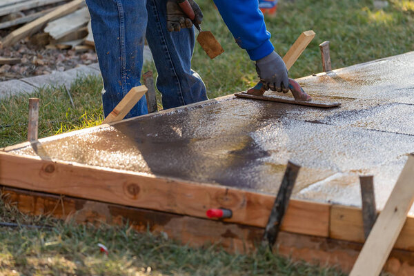Работник строительства сглаживание мокрого цемента с помощью лопаточных инструментов
