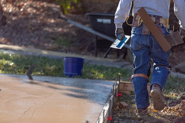 Travailleur de la construction avec des outils de truelle près du ciment humide de plate-forme — Photo