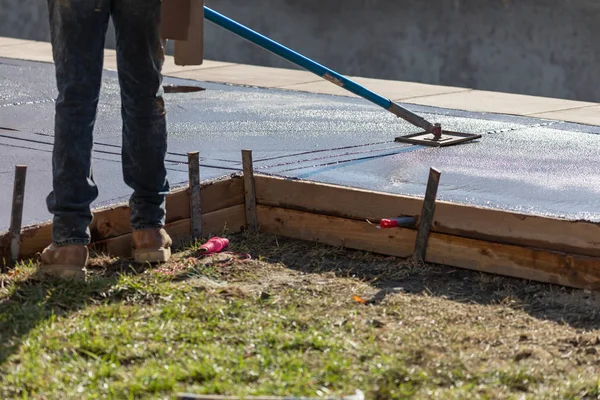 Trabajador de la construcción suavizando el cemento húmedo con herramienta de borde de mango largo — Foto de Stock