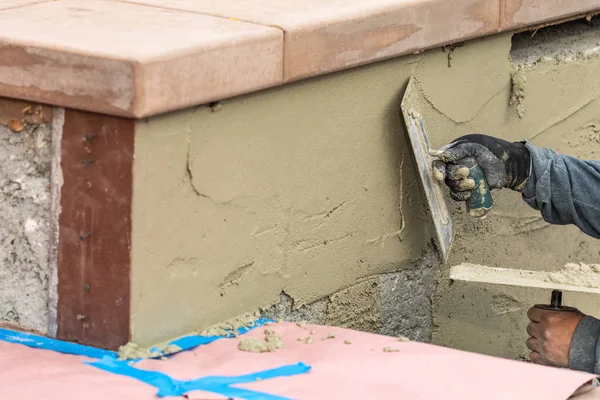 Trabalhador da telha aplicando cimento com espátula na construção da piscina Sit — Fotografia de Stock