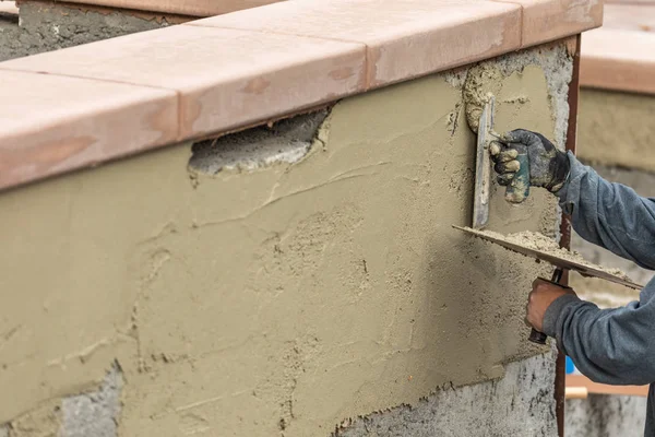 Trabalhador da telha aplicando cimento com espátula na construção da piscina Sit — Fotografia de Stock