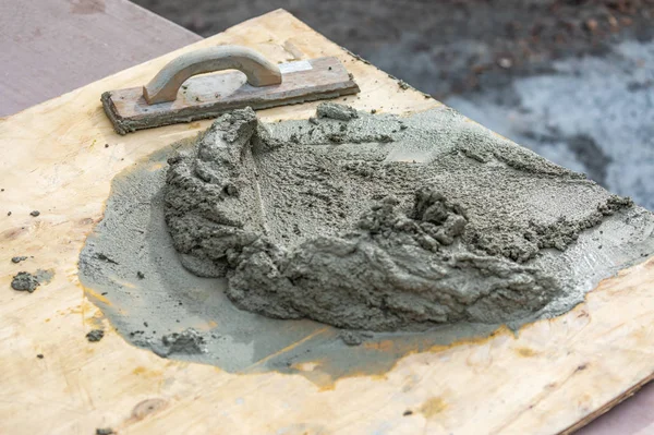 Houten vlotter zittend in de buurt van natte cement aan boord op bouwplaats — Stockfoto