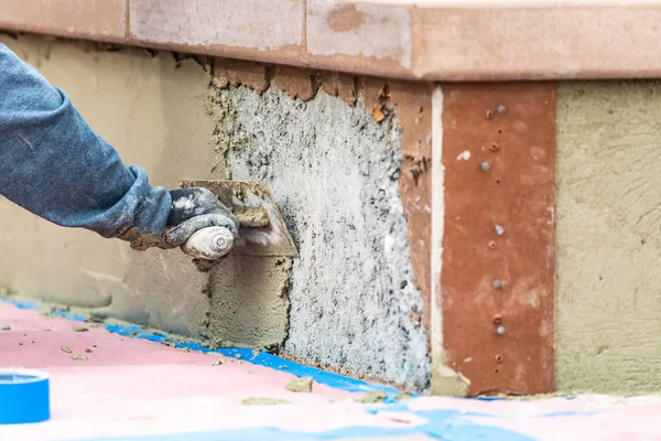 Плитка працівник застосування цементу з шпателем в басейн будівництва сидіти — стокове фото