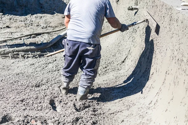 Travailleur de la construction de piscine travaillant avec un Bullfloat sur béton humide — Photo