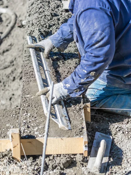 Pool byggnadsarbetare arbetar med en smidigare stav på våt betong — Stockfoto