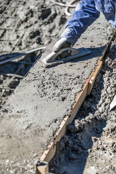 Trabalhador da construção da piscina que trabalha com flutuador de madeira no concreto molhado — Fotografia de Stock