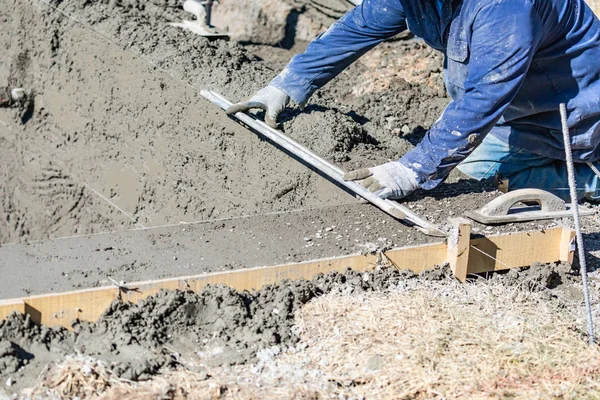 Trabalhador da construção da associação que trabalha com uma haste mais lisa no concreto molhado — Fotografia de Stock