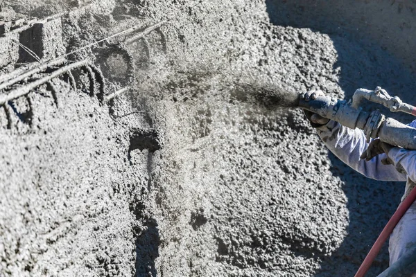 Travailleur de la construction de la piscine tirant sur le béton, le béton projeté ou le Gunite à travers le tuyau — Photo