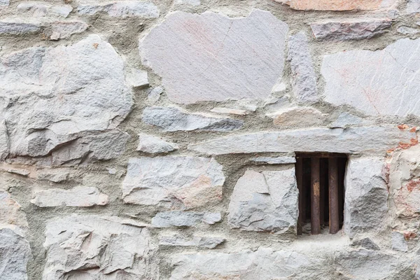 Oude stenen muur met kleine ijzeren gestreepte gevangeniscel venster — Stockfoto