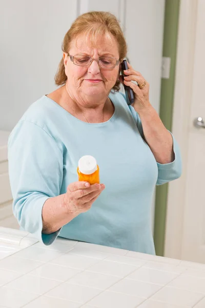 Mujer adulta mayor en el teléfono celular sosteniendo la botella de prescripción —  Fotos de Stock