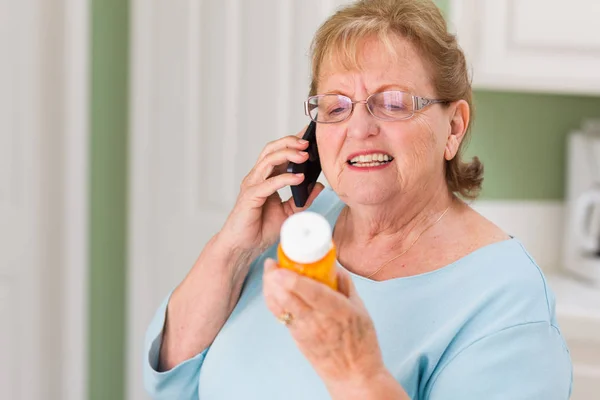 Senior volwassen vrouw op mobiele telefoon bedrijf voorschrift fles — Stockfoto