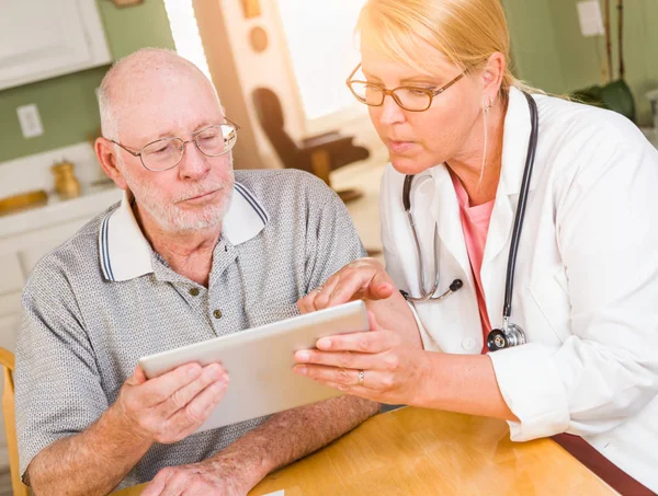 Kvinnlig läkare eller sjuk sköterska visar Senior man touch pad dator hemma. — Stockfoto