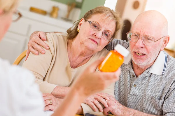 Médico o enfermera explicando medicamentos recetados a pareja adulta mayor . — Foto de Stock