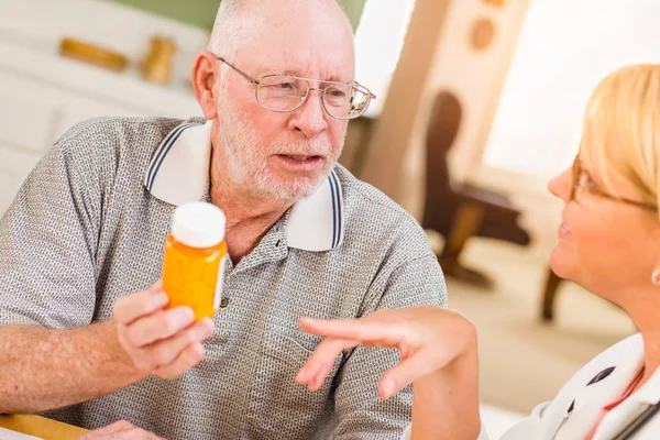 Médico o enfermera explicando la medicina de la prescripción al hombre mayor atento . — Foto de Stock