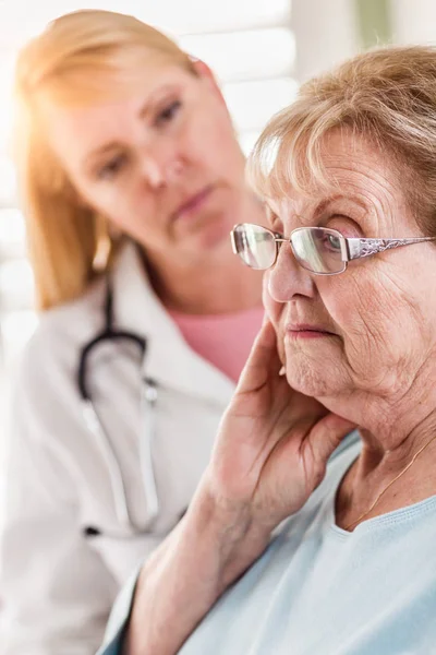 Melancólica mujer adulta mayor siendo consolada por una doctora o enfermera . — Foto de Stock