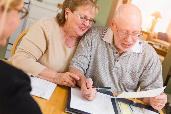 Pareja de adultos mayores revisando documentos en su casa con el agente al firmar . —  Fotos de Stock