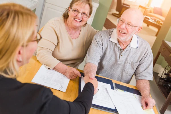 Senior erwachsenes Paar beim Unterschreiben von Dokumenten in seinem Haus mit Agenten. — Stockfoto