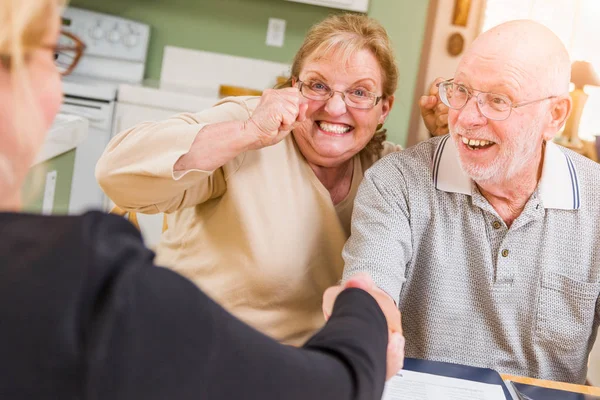 Pareja de adultos mayores celebrando más de documentos en su casa con el agente al firmar . —  Fotos de Stock