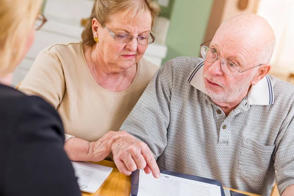 Senior volwassen paar gaan over documenten in hun huis met agent bij de ondertekening. — Stockfoto