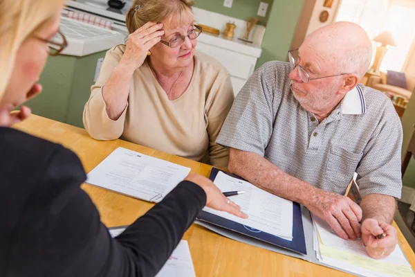 Pareja de adultos mayores revisando documentos en su casa con el agente al firmar . — Foto de Stock