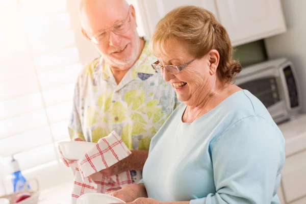 Senioren erwachsenes Paar hat Spaß beim gemeinsamen Geschirrspülen in der Küche ihres Hauses. — Stockfoto