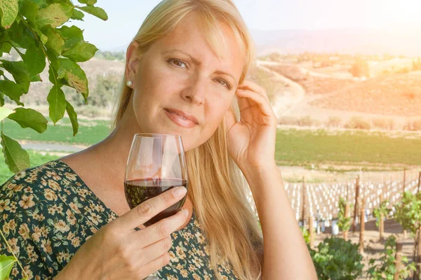 Mulher adulta jovem bonita desfrutando de um copo de degustação de vinhos na vinha — Fotografia de Stock