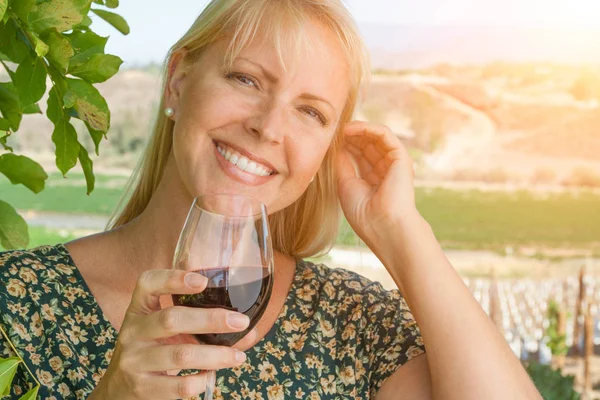 Mulher adulta jovem bonita desfrutando de um copo de degustação de vinhos na vinha — Fotografia de Stock