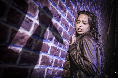 Male Shadow Figure With Knife Threatens Frightened Young Woman Against Brick Wall clipart