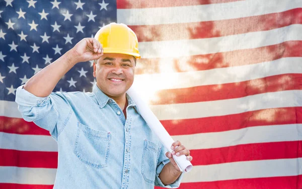 Contratista masculino hispano con planes Blueprint con sombrero duro en frente de la bandera estadounidense . —  Fotos de Stock