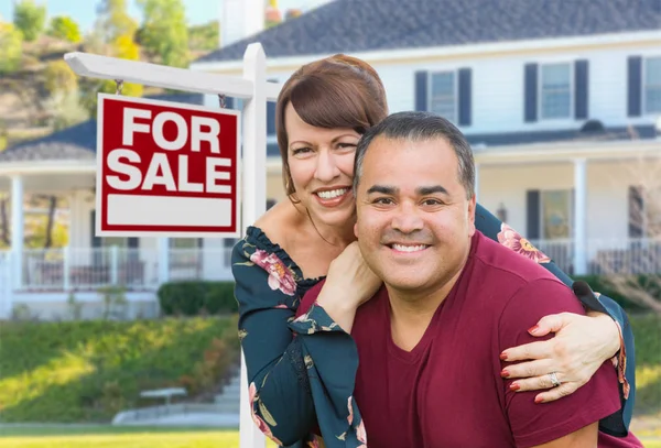 Mixed Race Young Adult Couple In front of House and For Sale Real Estate Sign . — стоковое фото