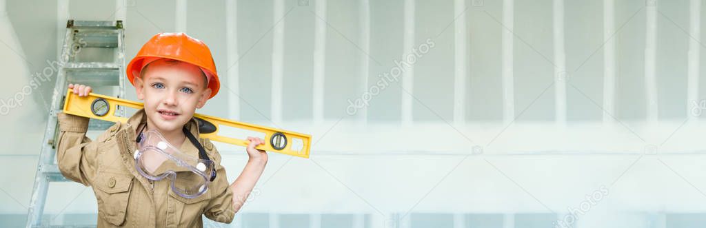 Cute Young Boy Dressed As Contractor Holding Level Against Dywall Banner Background with Ladder.