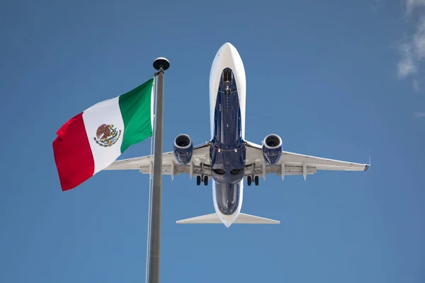 Vista inferior del avión de pasajeros ondeando la bandera de México en el poste — Foto de Stock