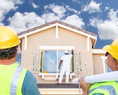 Male and Female Contractors Overlooking Painter Painting House clipart