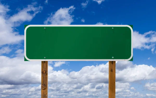 Señal verde en blanco con postes de madera sobre cielo azul y nubes —  Fotos de Stock