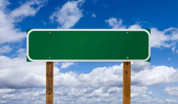 Blank Green Road Sign with Wooden Posts Over Blue Sky and Clouds — Stock Photo, Image