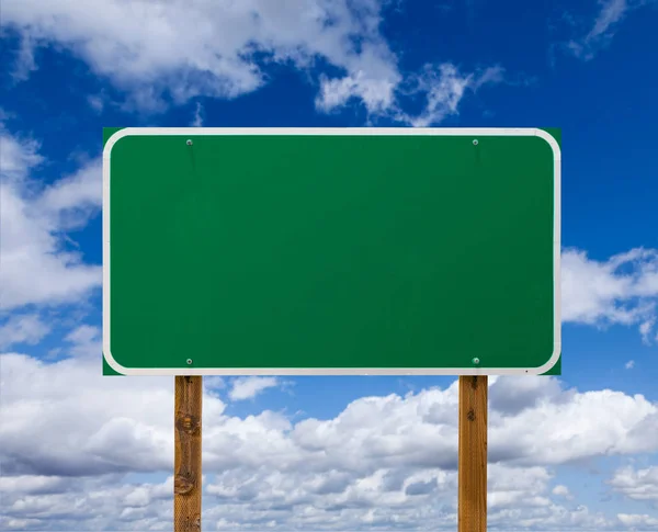 Leeres grünes Straßenschild mit Holzpfählen über blauem Himmel und Wolken — Stockfoto