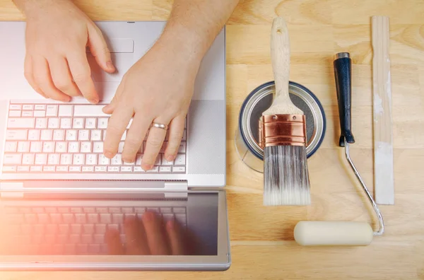 Måla verktyg bredvid Handyman använda laptop overhead — Stockfoto