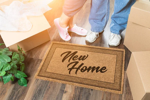 Uomo e donna disimballaggio vicino a nuova casa tappetino di benvenuto, scatole mobili e pianta — Foto Stock