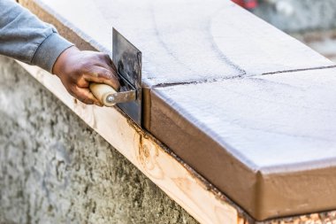 İnşaat işçisi paslanmaz çelik kenarı kullanıyor Islak çimento Yeni Havuz Çevresinde Başa Çıkma