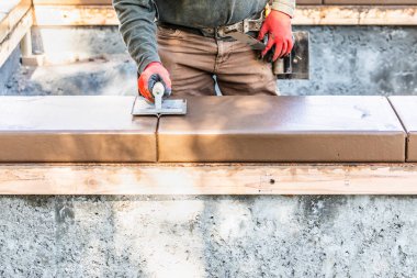 İnşaat işçisi ıslak çimentoya elle dokunarak yeni havuzun etrafını kontrol ediyor.