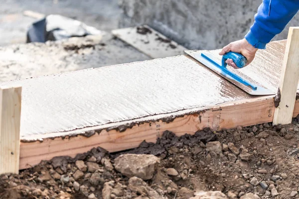 Trabalhador da construção civil usando espátula em cimento molhado formando enfrentamento em torno de nova piscina — Fotografia de Stock