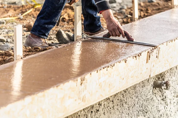 Operaio edile che utilizza cazzuola di legno sul cemento bagnato che forma far fronte intorno a una nuova piscina — Foto Stock