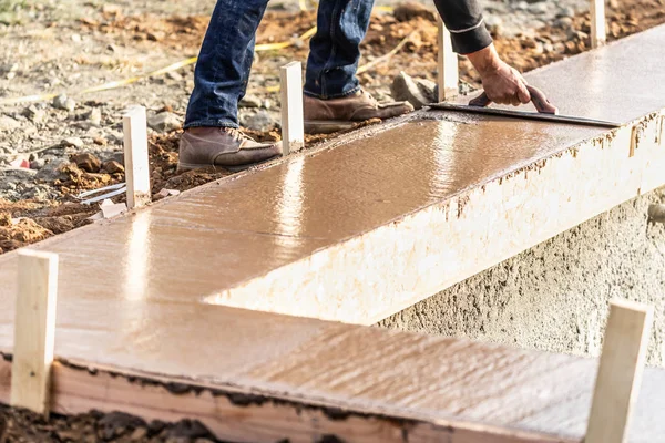 Travailleur de la construction utilisant une truelle en bois sur du ciment humide formant une capacité d'adaptation autour d'une nouvelle piscine — Photo