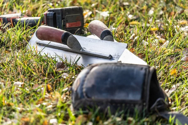Tropas de cimento e ferramentas na grama no canteiro de obras — Fotografia de Stock