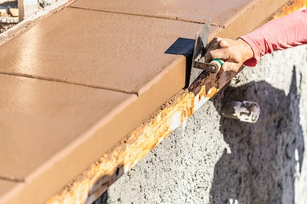 Trabajador de la construcción usando el borde del acero inoxidable en el cemento húmedo que forma el hacer frente alrededor de la piscina nueva —  Fotos de Stock