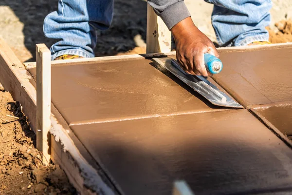 Travailleur de la construction utilisant la truelle sur ciment humide formant coping autour d'une nouvelle piscine — Photo